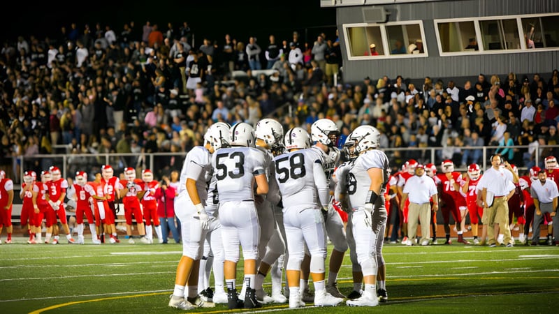 Eine Gruppe von Fußballspielern der Xavier High School steht gemeinsam auf dem Spielfeld vor einer großen Zuschauermenge.