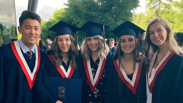 Eine Gruppe von Absolventinnen und Absolventen der Yale Secondary School steht im Freien vor Bäumen und Grünflächen.