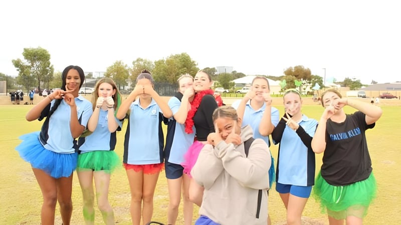 Eine Gruppe junger Athletinnen posiert auf einem Grasfeld auf dem Campus des Yanchep Secondary College.