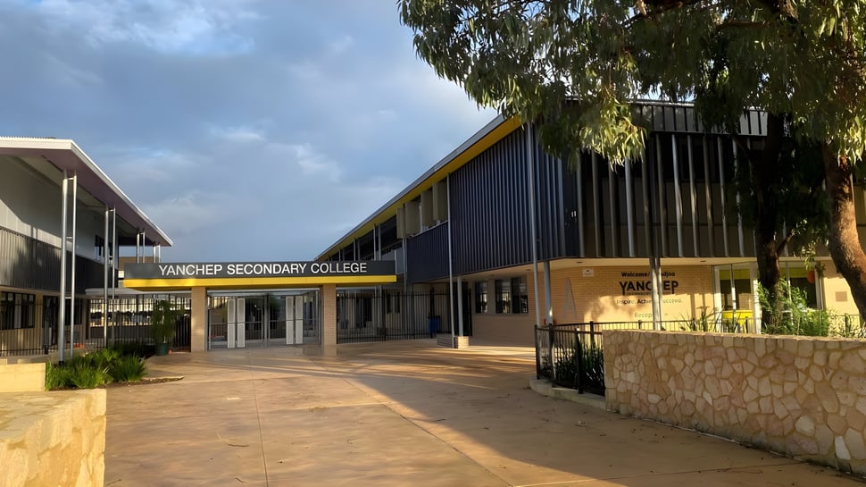 Das moderne mehrstöckige Schulgebäude des Yanchep Secondary College ist von Bäumen und einem gepflasterten Weg umgeben.