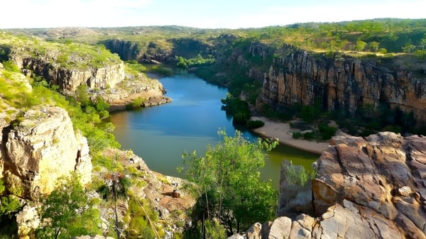 Ein ruhiger See mit steilen Klippen und grüner Landschaft unter blauem Himmel, umgeben von Natur nahe der Yanchep Secondary College.