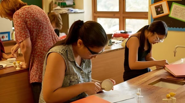 Drei Schülerinnen der Yehudi Menuhin School sitzen an einem Tisch und sind mit Lesen und Schreiben beschäftigt.
