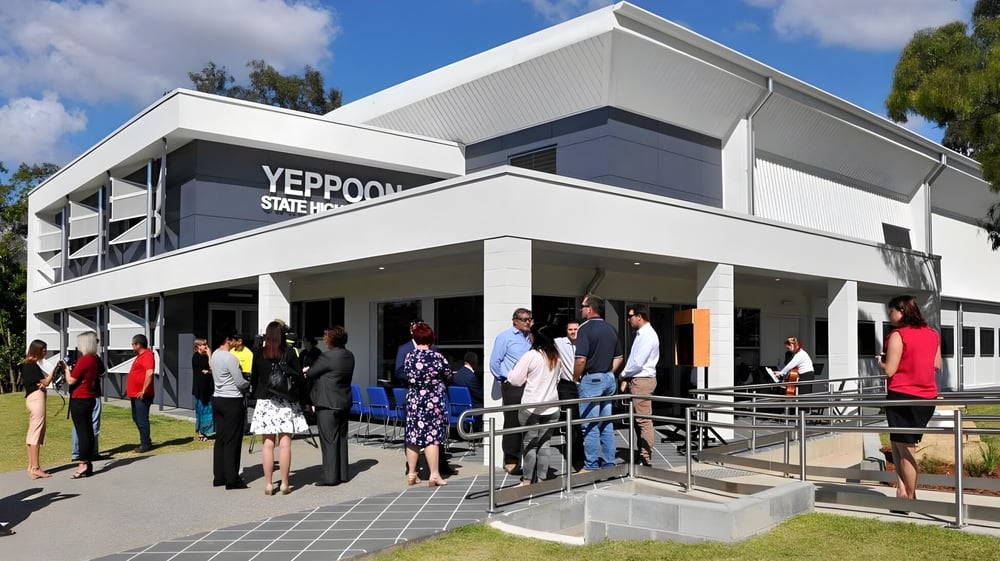 Das moderne mehrstöckige Gebäude der Yeppoon State High School mit Menschen vor dem Haupteingang und einer Rasenfläche im Vordergrund.