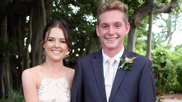 Ein junges Paar steht lächelnd in einem grünen Außenbereich auf dem Gelände der Yeppoon State High School.