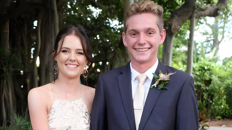 Ein junges Paar steht lächelnd in einem grünen Außenbereich auf dem Gelände der Yeppoon State High School.