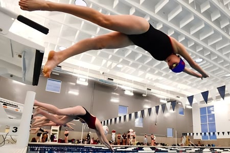 Eine Schülerin der Yeronga State High School führt einen Sprung im Hallenbad während eines Schwimmwettbewerbs durch.