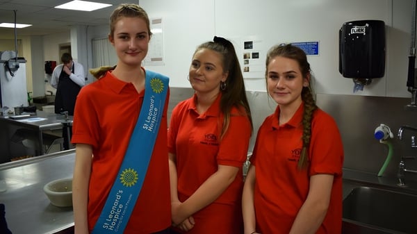 Drei Schülerinnen in roten Uniformen stehen in der Küche auf dem Campus des York College.