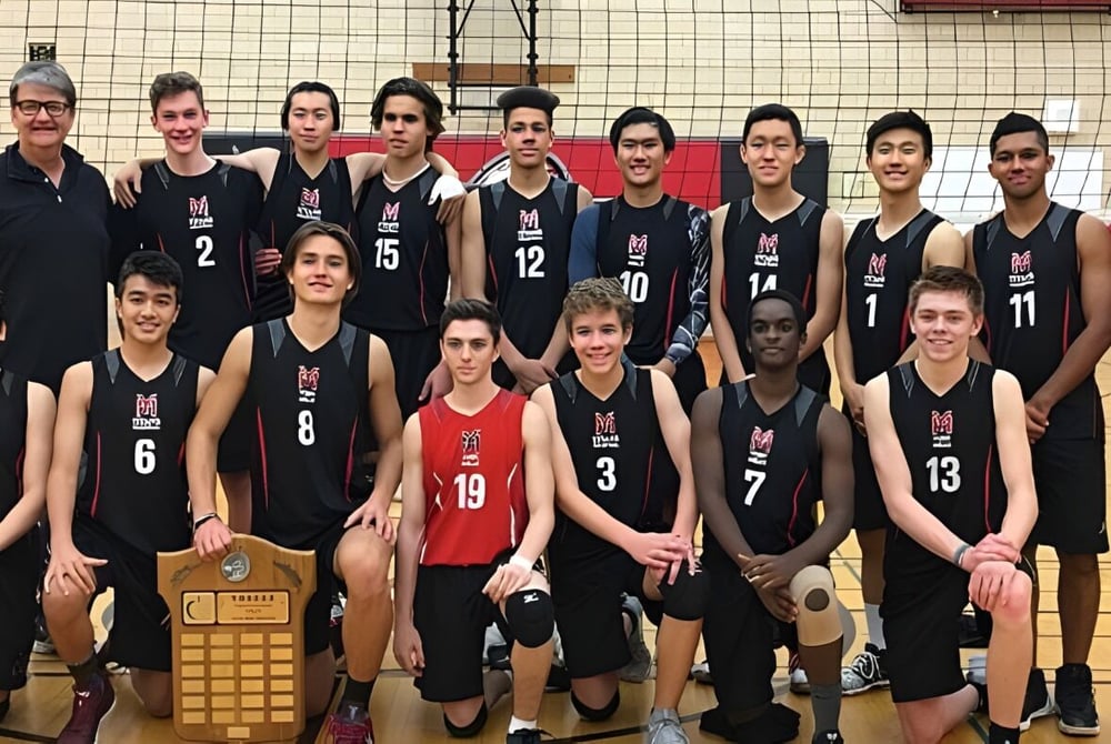Die Volleyballmannschaft des York Mills Collegiate Institute posiert mit einem Pokal in der Turnhalle.
