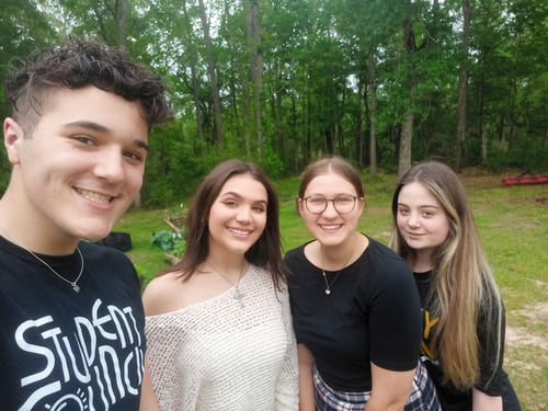 Ein Junge und drei Mädchen vor einem Wald