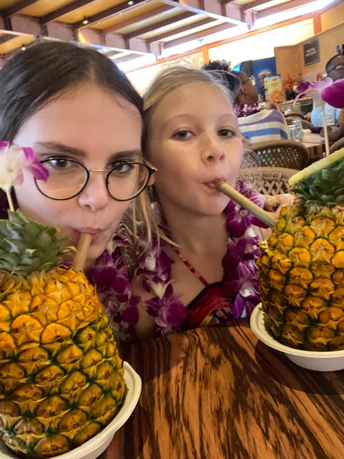 Zwei Mädchen trinken aus einer Ananas