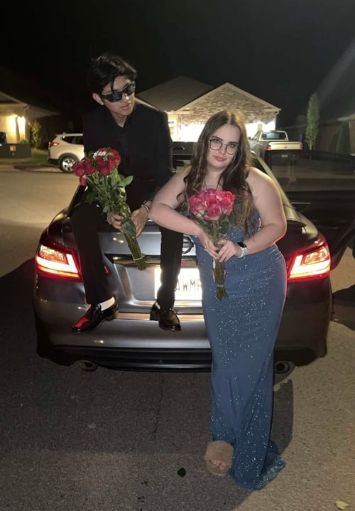 Zwei Jugendliche mit Rosen in den Händen auf einem Auto