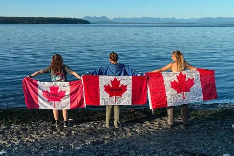 drei Schülerinnen Kanada am Meer mit Flaggen