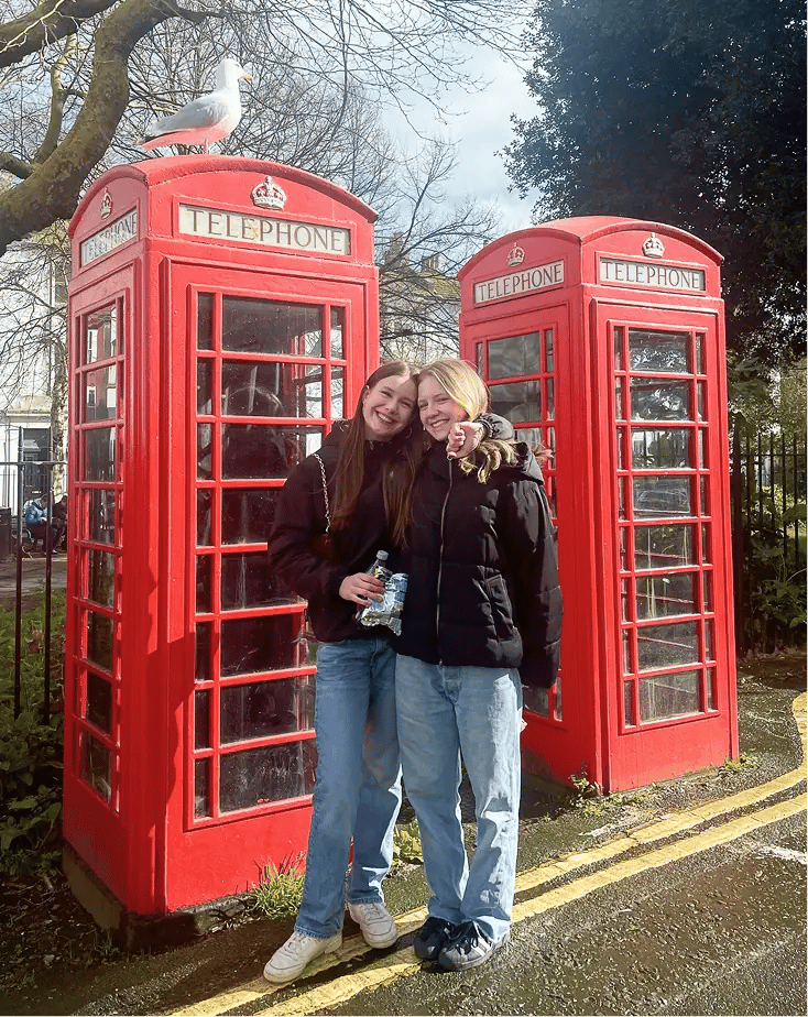 zwei Schülerinnen England rote Telefonzelle