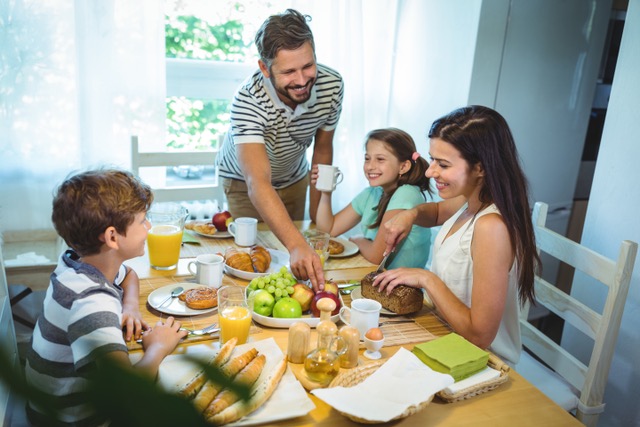 Eine Familie sitzt gemeinsam  am gedeckten Frühstückstisch.