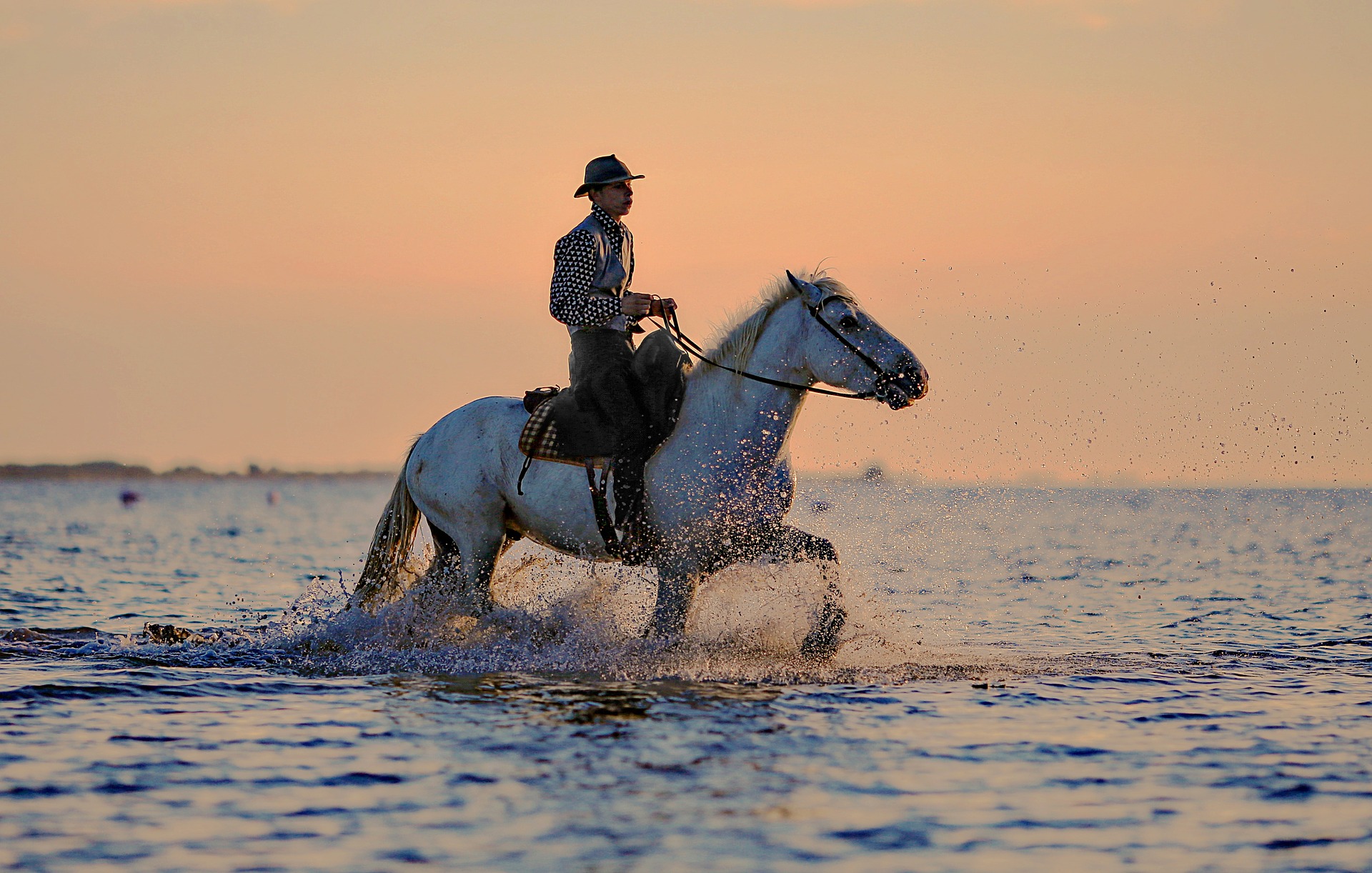 Ein Mann reitet ein Pferd während des Sonnenuntergangs am Strand