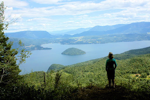 Eine Teilnehmerin steht auf einem Berg und blickt auf ein großes Gewässer