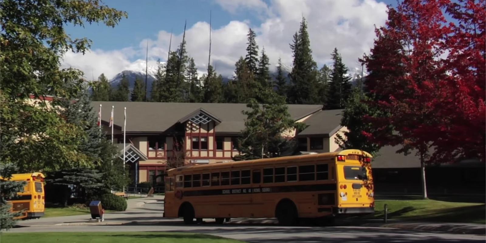 Ein Schulbus fährt zu einer High School in Kanada im Sea to Sky Schuldistrikt, man sieht bunte Laubbäume